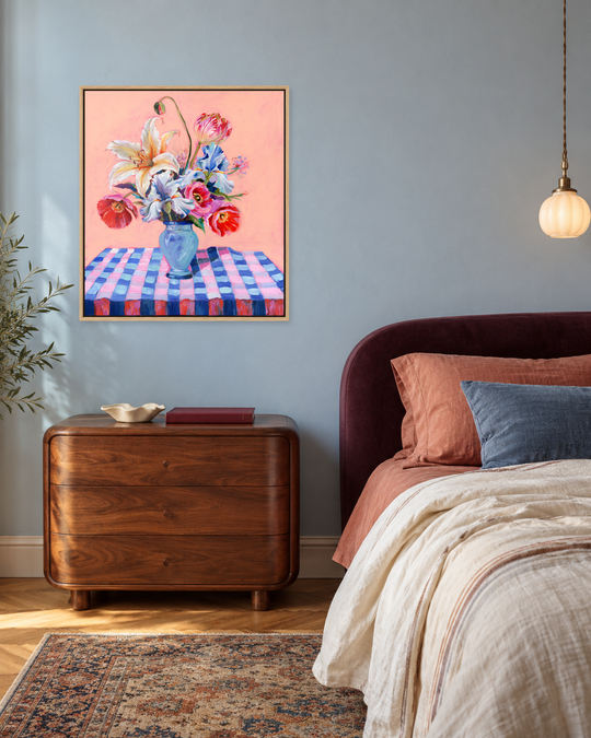 Digital bedroom mockup of The Celebration original oil painting against a blue wall beside a plum headboard and walnut chest. Original artwork photograph preserved; framing and room scale are illustrative.