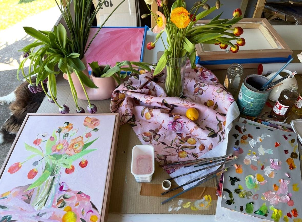 Studio table with painting, flowers, fabric and palette